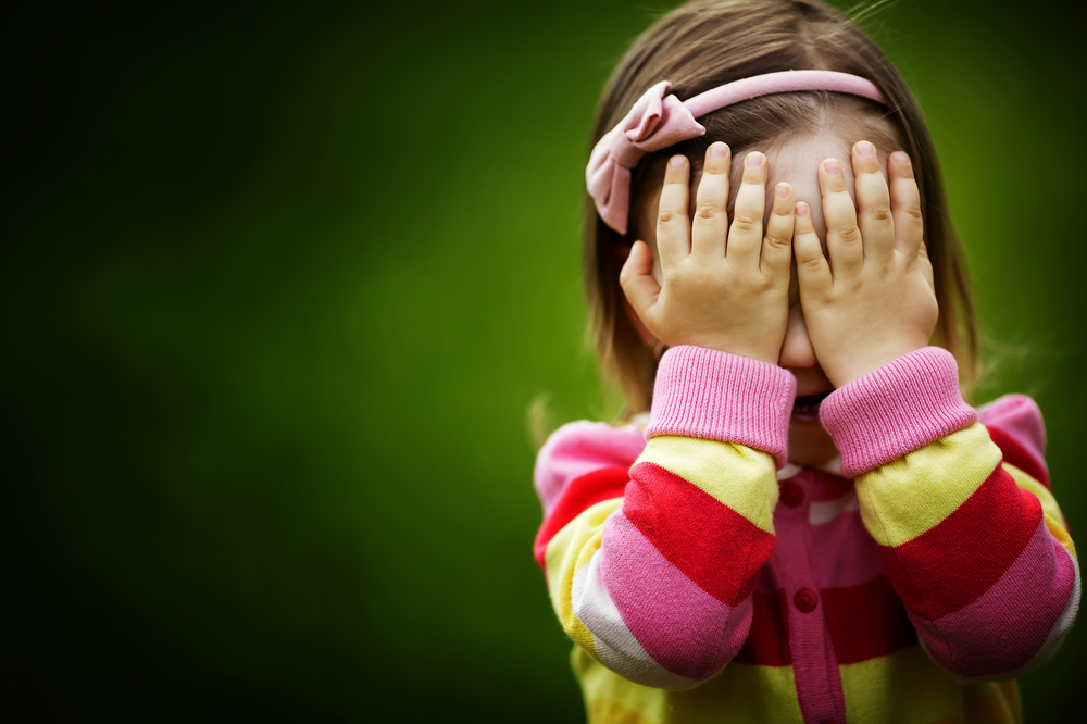 Niña con manos tapándose la cara:jugando al veo veo